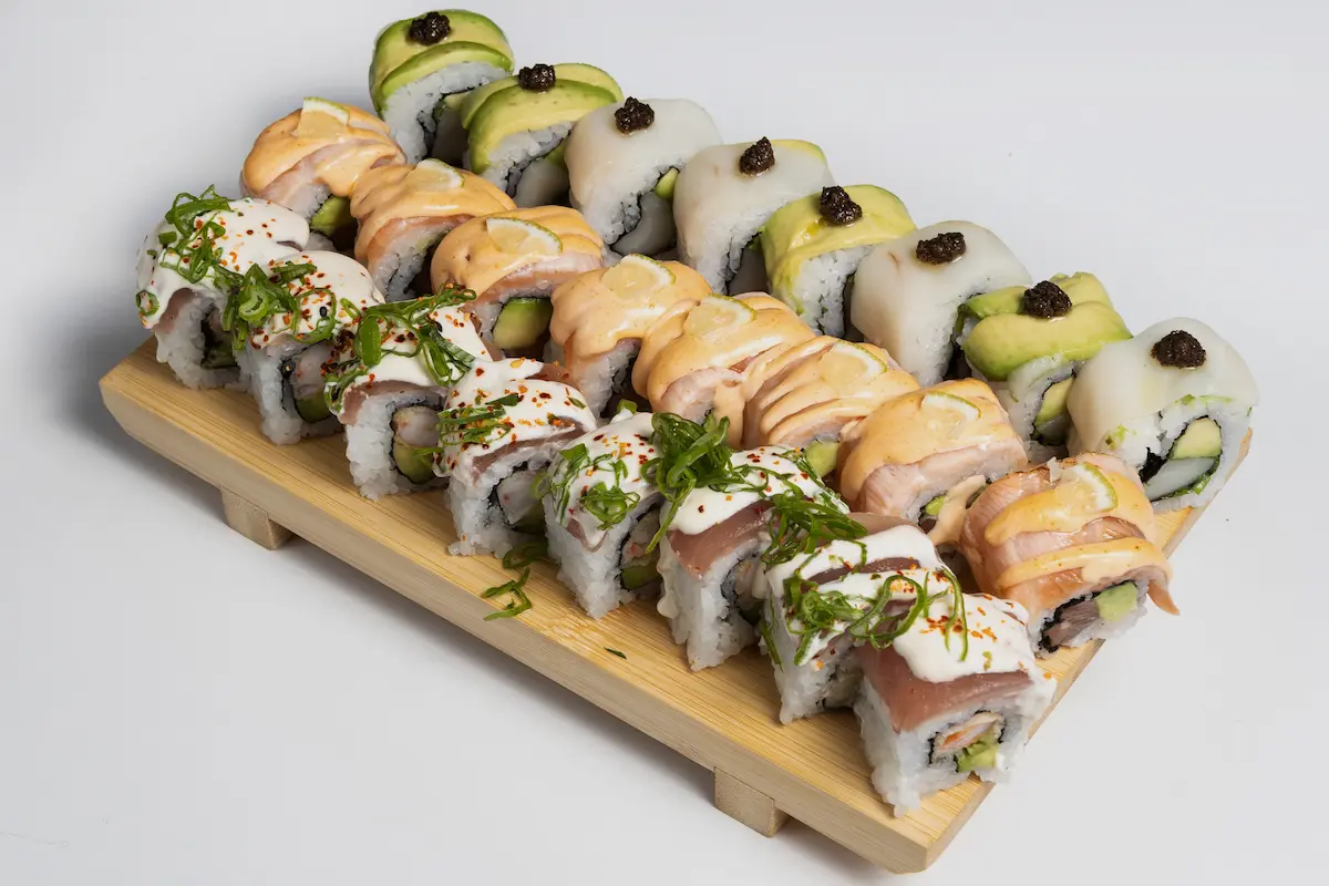 Bandeja de sushi premium de Amaru Sushi Bar con surtido de nigiris, sashimis y rolls especiales, incluyendo cortes de salmón, atún, pez mantequilla y gamba, decorados con salsas y toppings gourmet sobre bandeja de presentación elegante