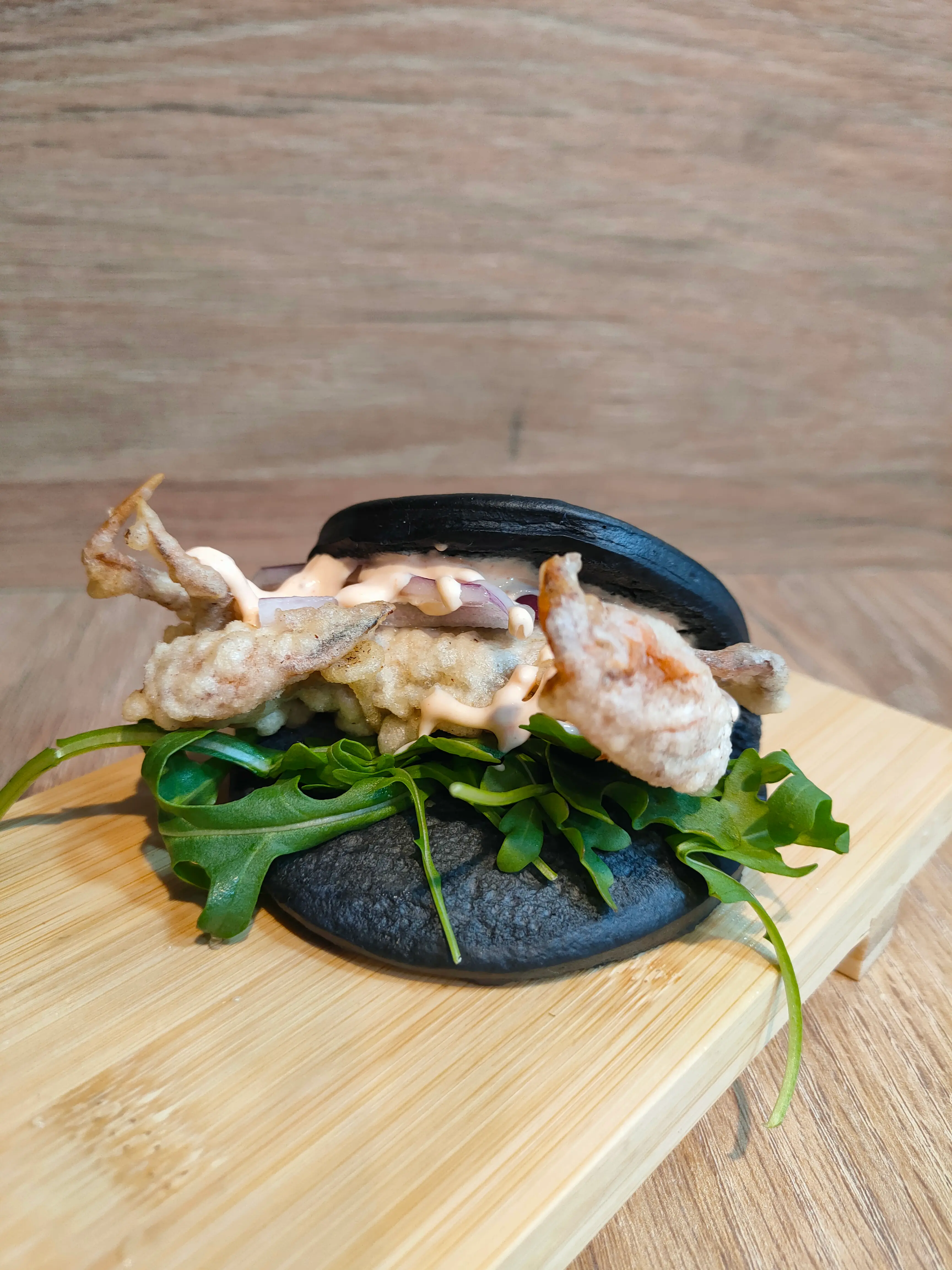 Bao negro de Amaru Sushi Bar con pan al vapor de tinta de calamar, relleno de carne o mariscos, acompañado de verduras frescas, salsa especial y presentación moderna